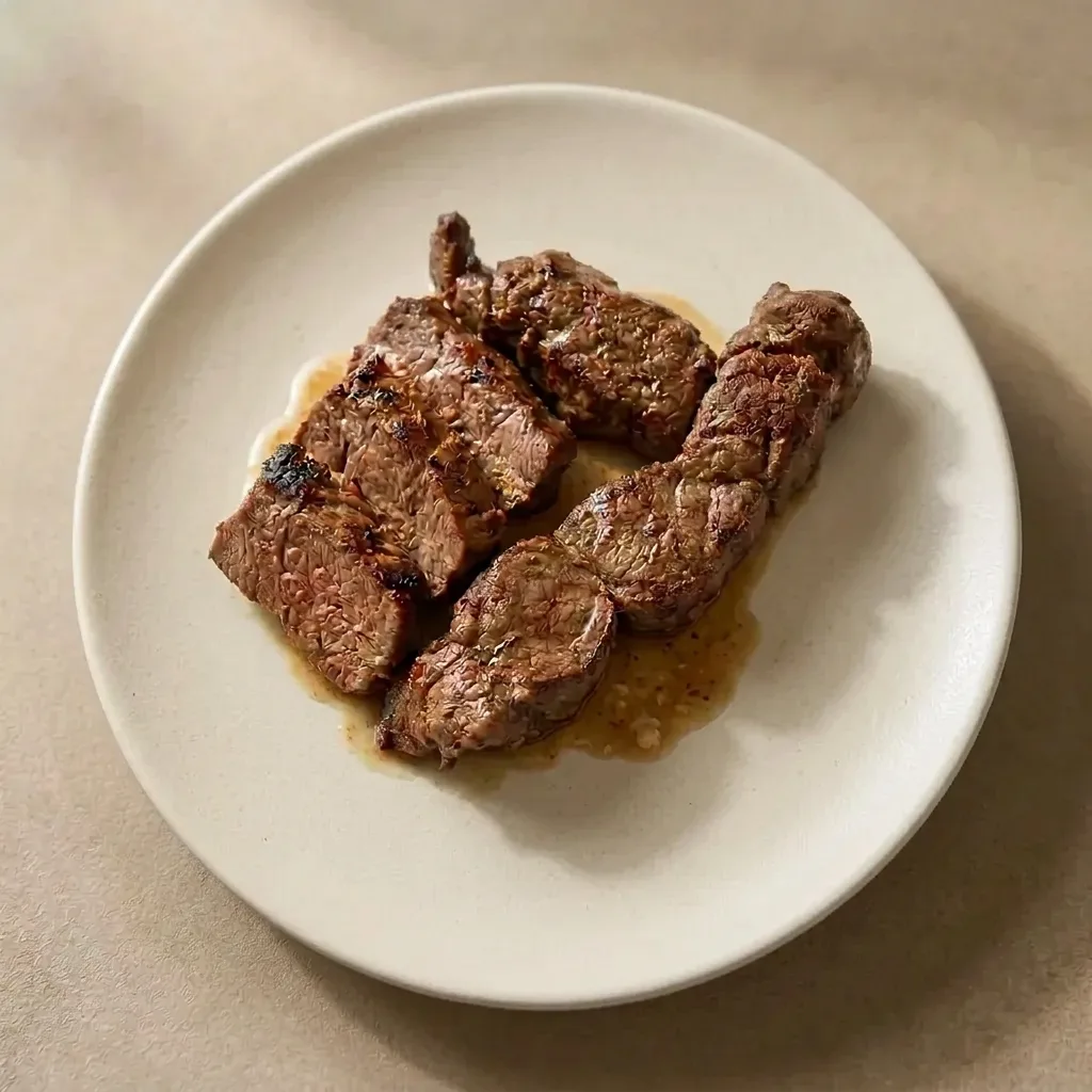 Sliced chargrilled lamb backstrap plated on its own on a white ceramic plate, sumac and saffron crusted